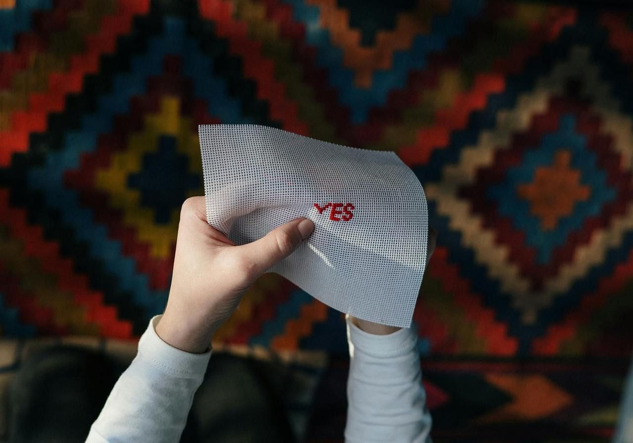 A person holds a paper displaying the word "yes" in bold letters, conveying a positive affirmation.